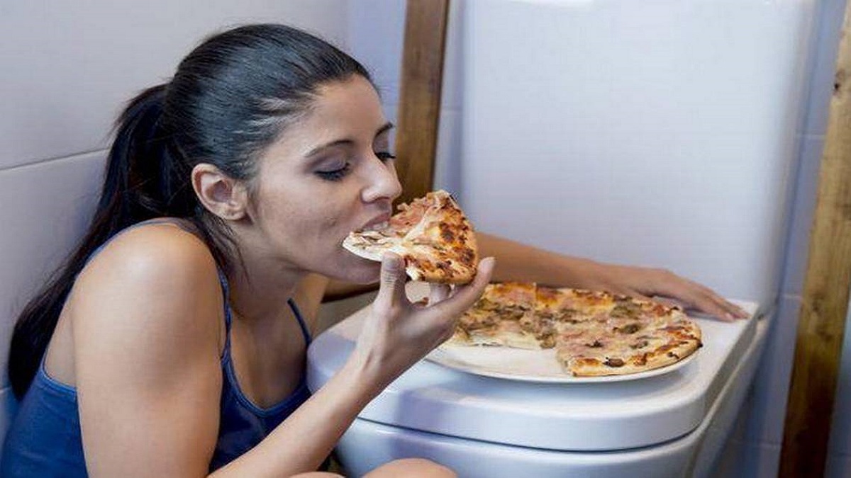 imagen de una joven comiendo en el cuarto de baño preparándose para vomitar lo comido TifloEduca