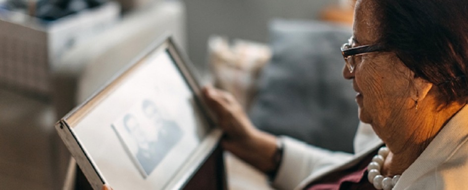 covid-19: imagen de un anciana mirando una foto de su marido fallecido.