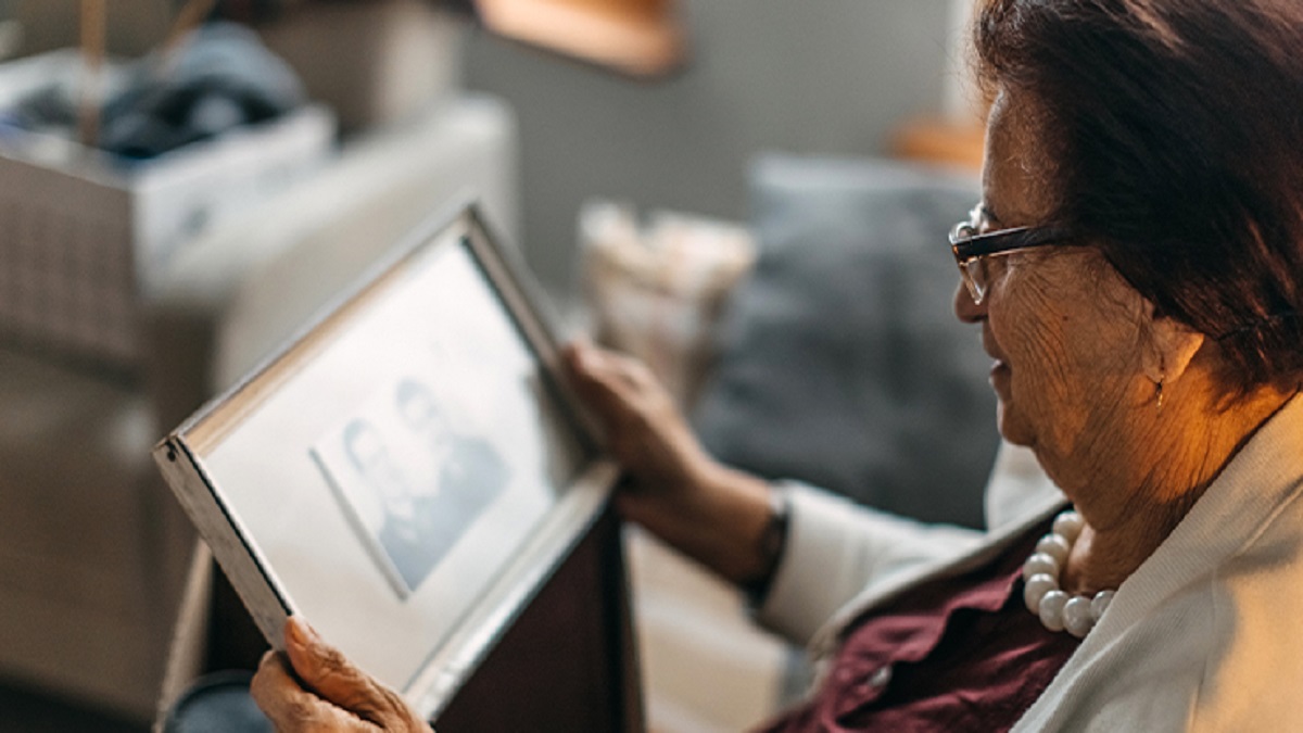 covid-19: imagen de un anciana mirando una foto de su marido fallecido.