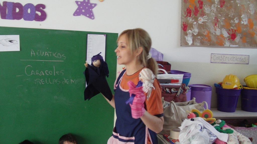 imagen de una profesora usando títeres para dar una clase.