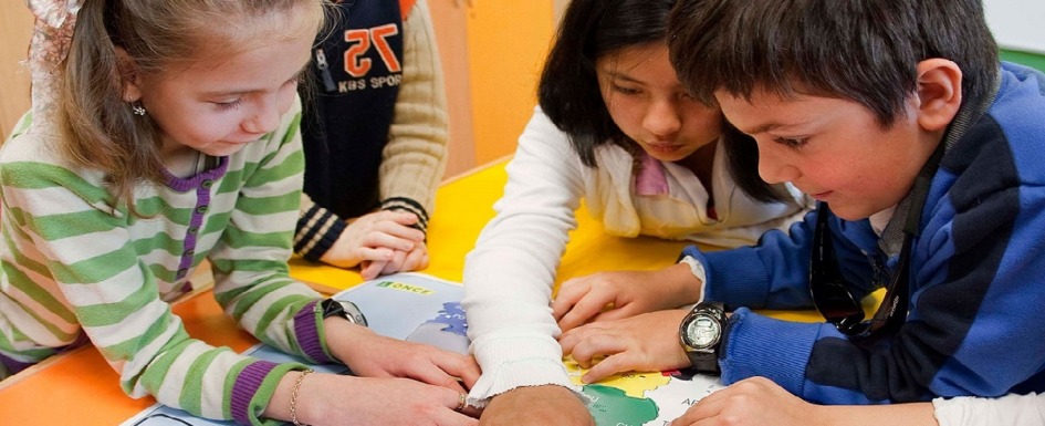 niños con discapacidad visual estudiando sobre un mapa en relieve.
