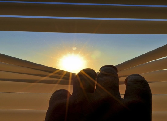 Vivir el Covid a ciegas. Imagen de una mano deslizando una cortina hacia abajo dejando entrar el sol