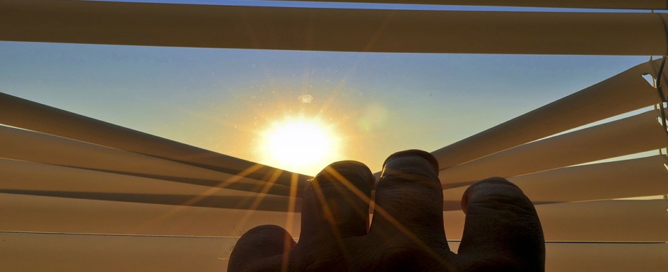 Vivir el Covid a ciegas. Imagen de una mano deslizando una cortina hacia abajo dejando entrar el sol