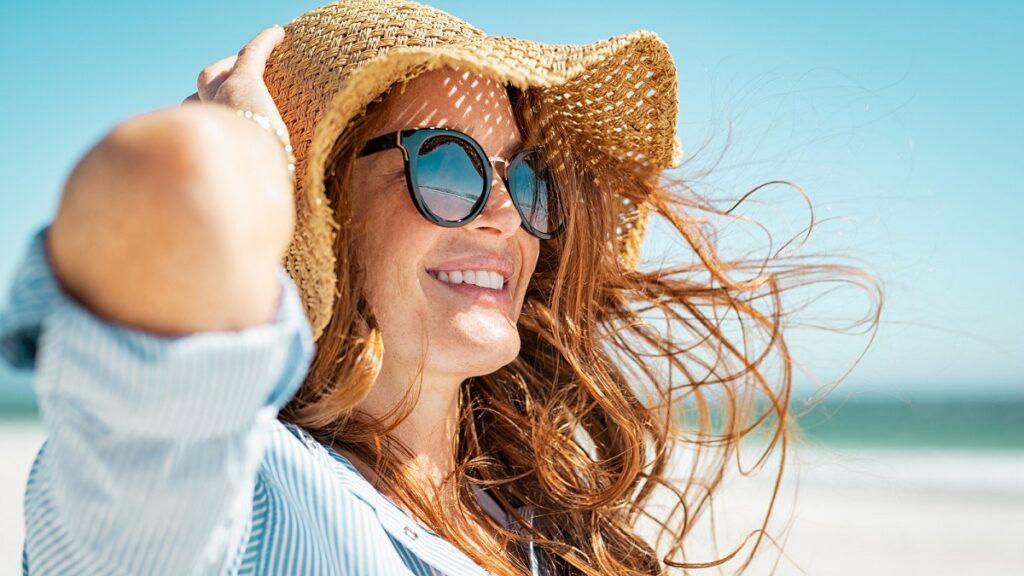 proteger ojos y piel: imagen de una mujer con sombrero y gafas de sol para protegerse de los efectos del sol