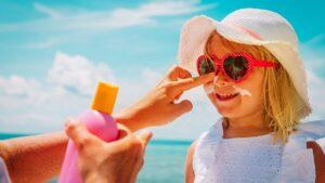 proteger ojos y piel: imagen de una madre aplicando crema solar a su hija