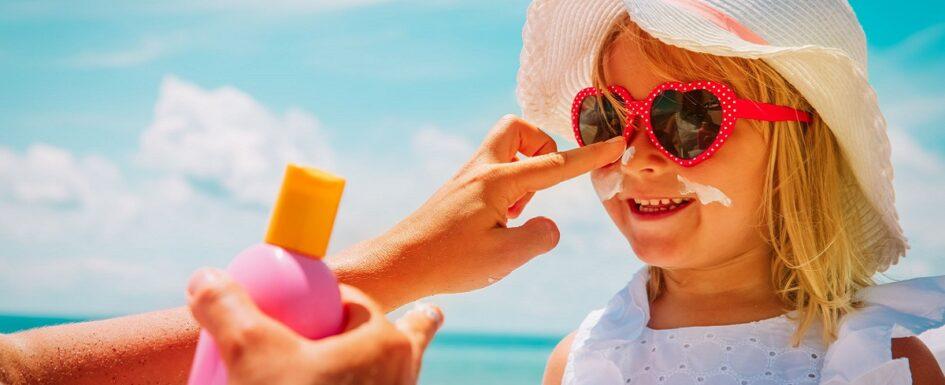 proteger ojos y piel: imagen de una madre aplicando crema solar a su hija