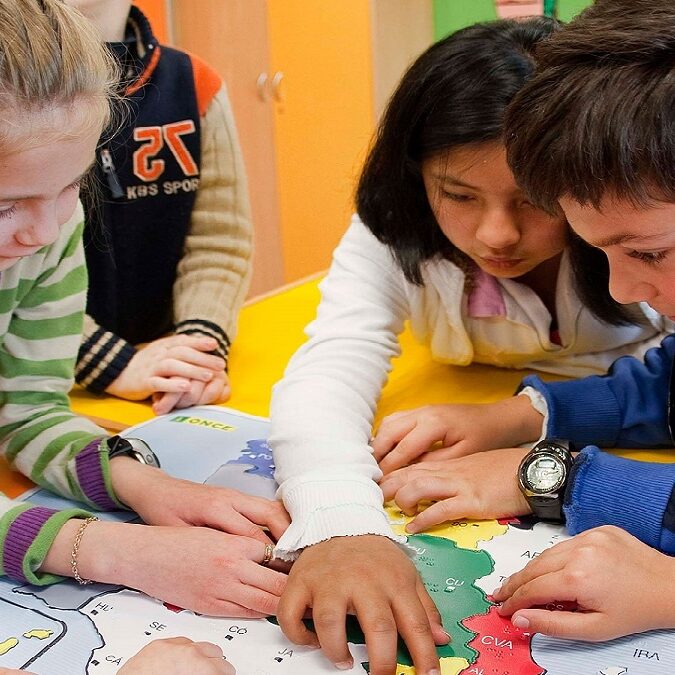 niños con discapacidad visual estudiando sobre un mapa en relieve.