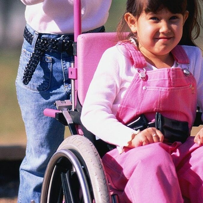 imagen de una niña con problemas de movilidad sentada en una silla de ruedas.
